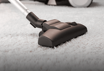 vacuuming of a white carpet by a black vacuum